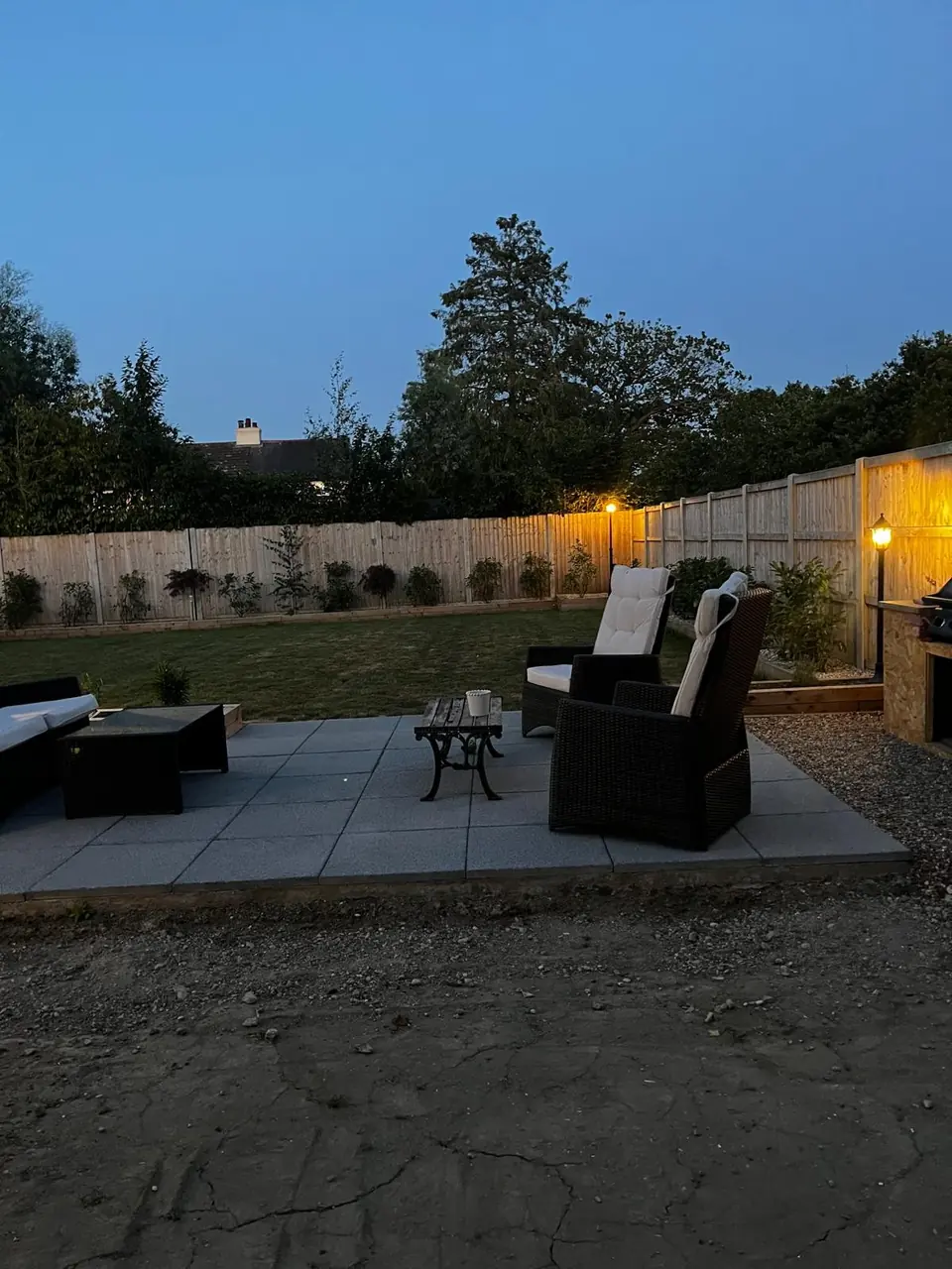 Finished planted borders and paved seating area lit at dusk