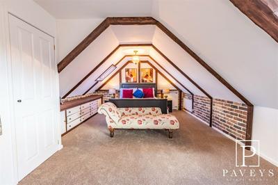 Loft bedroom with exposed beams and custom joinery